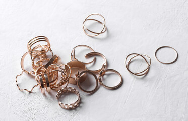 Many Gold rings of different shapes on a white concrete background. Jewelry store, beauty concept