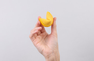 Fortune cookie in hand on gray background