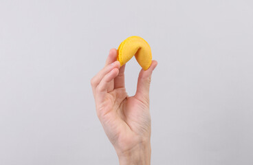 Fortune cookie in hand on gray background