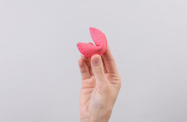 Fortune cookie in hand on gray background