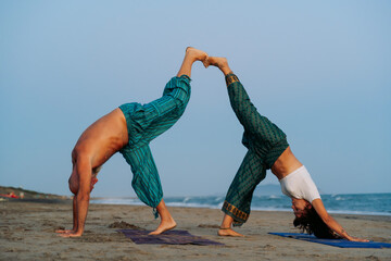 Couple Performing Partner Yoga Pose on the Beach at Sunset