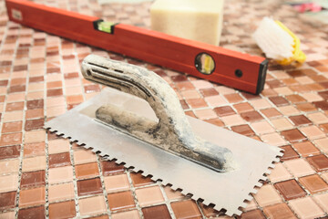 old comb for applying tile adhesive in the center of the frame against the background of glass...