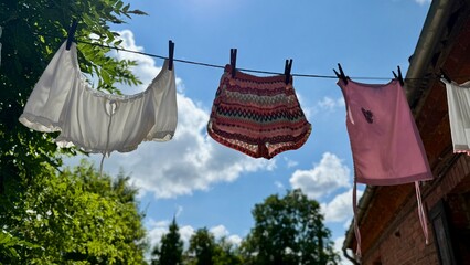 Clothes drying on a line in a sunny courtyard with rustic red brick buildings and a bright blue sky...