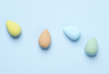 Make-up sponges, cosmetic beauty blenders on blue background. Top view. Flat lay