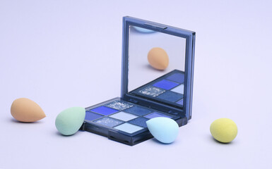 Make-up sponges, cosmetic blenders and eyelash shadow palette on beige background. Beauty products.