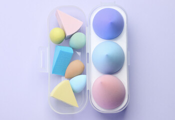 Different Make-up sponges, cosmetic blenders set on purple background. Beauty products.