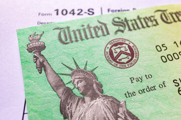 Close-up of a U.S. Treasury tax refund check and IRS form 1042-S on top of a financial statement....