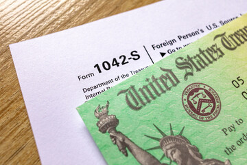 Close-up of a U.S. Treasury tax refund check and IRS form 1042-S on top of a financial statement....
