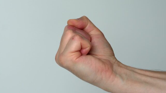 abuse and conflict.
Aggressive behavior of a guy on a white background.
A man shows a fist threatening someone