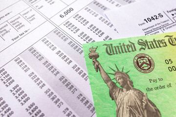 Close-up of a U.S. Treasury tax refund check and IRS form 1042-S on top of a financial statement....