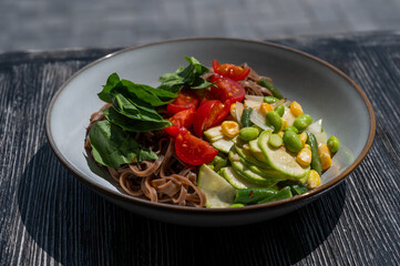 Top view of a dish of buckwheat noodles with vegetables. 