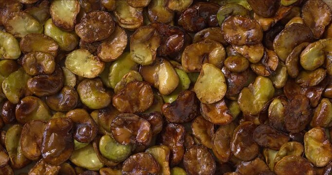 Homemade roasted fava beans (Vicia faba) as a background texture. Flat lay, table spin. 