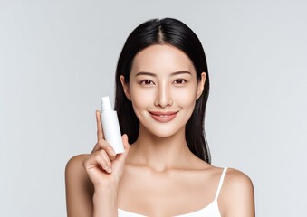 Woman holding skincare product against gray background