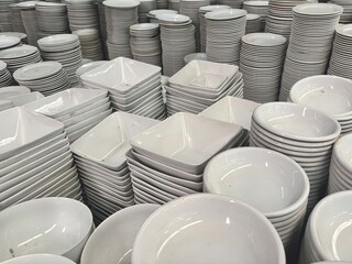 An expansive collection of various white ceramic dishes, including plates, bowls, and square...