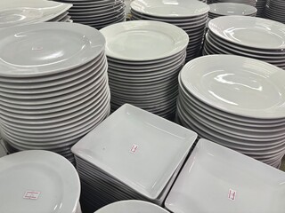 stack of plates. An expansive collection of various white ceramic dishes, including plates, bowls,...