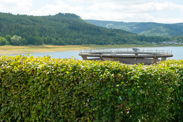 Der Blick über die Hecke zeigt den oberen Rand vom Übrlaufturm in der Innerstetalsperre . Einen...
