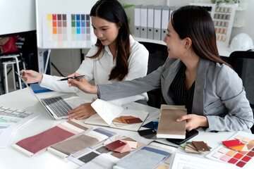 Two Asian female interior designers discussing and examining material