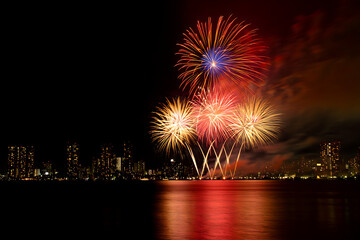 Fireworks reflecting on the water illuminate the cityscape at night