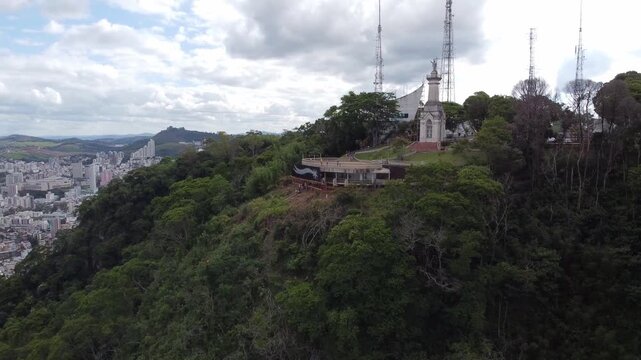 MIRANTE DO MORRO DO CRISTO, JUIZ DE FORA, MINAS GERAIS, BRAZIL - DECEMBER 20, 2021: Drone view of the highest lookout in the city. Panorama showing the hilltop with antennas and the city below.