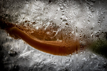 close-up of a refreshing clear drink with slices of citrus fruit and ice, viewed through the...