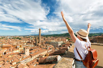 Young tourist with arms raised in front of the panoramic view of the city of Bologna - Italy