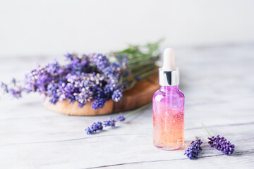 Dropper bottles with lavender cosmetic oil or face serum with fresh lavender flowers on white wooden rustic board. Herbal cosmetics and modern apothecary concept. Lavender beauty products