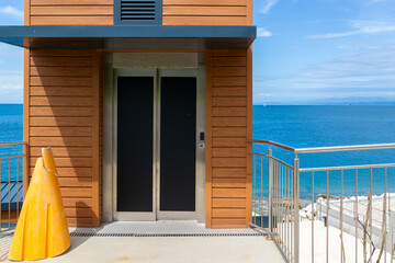 Modern Outdoor Elevator Connecting Levels of a Two-Level Beach. Contemporary Coastal Access and Sea View