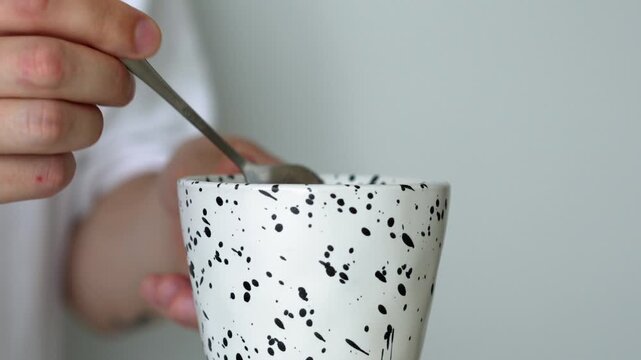A man stirs sugar in a cup with a teaspoon.
A hot drink in a man's hands on a white isolated background.
A cup with tea and a teaspoon
