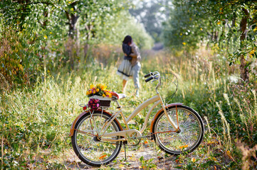 Fototapeta premium Picturesque moment showcasing a vintage bicycle with flowers, and a couple warmly embracing in a scenic countryside in out of focus