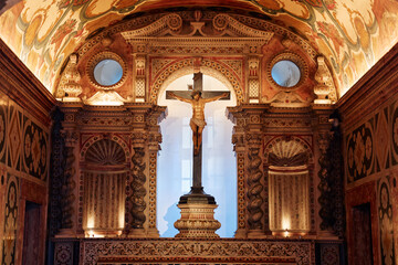 A beautifully decorated chapel featuring intricate frescoes and a central crucifix. The ornate...