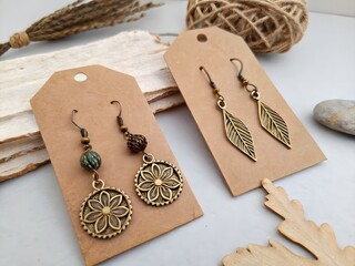 Close up of two pairs of earrings on brown tags with twine and wooden leaf decor