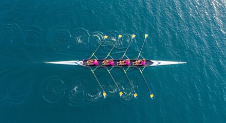 Team of four rowers in sync powering a racing shell through calm blue water, an aerial view of synchronized athletic effort.
