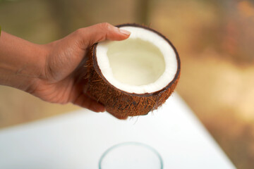 Person holding a coconut and pouring it into a glass cup.