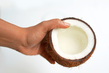 Coconut held in hand on white background.