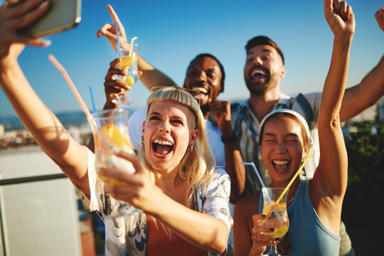 Group of cheerful multi-ethnic friends taking selfie and having fun at rooftop party - Powered by Adobe