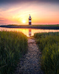 Sonnenuntergang an einem kleinen Leuchtturm an der deutschen Nordseek&uuml;ste.