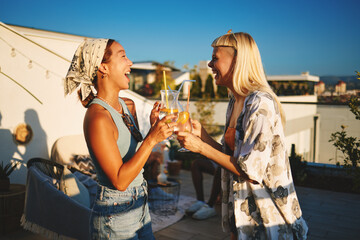 Friends enjoying drinks and laughing together at a rooftop party