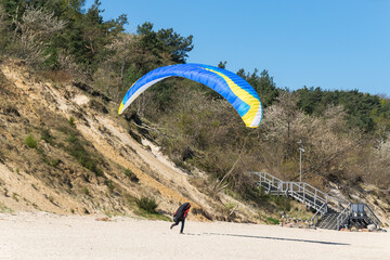 a paraglider landing on a seaside beach