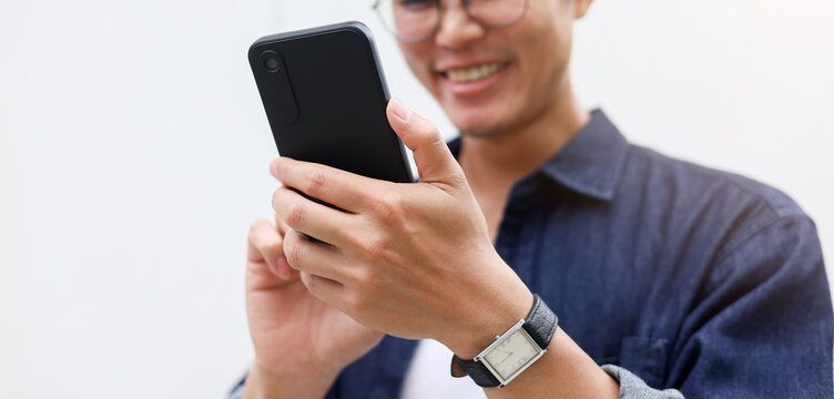 close up young asian man hand hold mobile cell phone device to play social media or read news website on smartphone for relaxing and leisure lifestyle concept