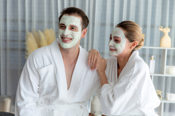 Blissful couple in bathrobe with facial cream mask enjoying serene ambiance of spa salon resort or...