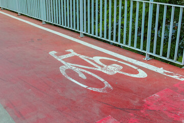 Red painted bicycle lane marking with white bicycle symbol on urban street pavement