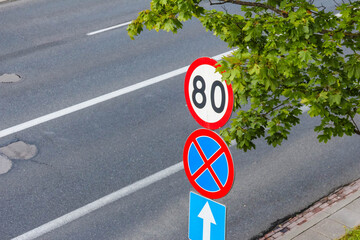 European road traffic signs showing speed limit and no parking regulations on street