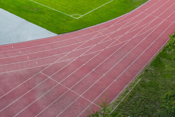Straight section of running track with multiple red lanes separated by white markings