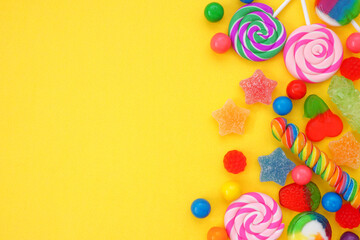 Colorful selection of candies. Top down view side border over a yellow background.