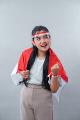 Indonesian woman wearing red and white accessories shows a proud and joyful expression while...