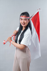 Cheerful young Asian woman celebrates Indonesia's Independence Day with red and white accessories...