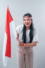 Energetic Indonesian woman cheerfully waves the national flag with a bright smile, expressing...