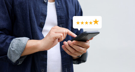 close up on customer man hand pressing on smartphone screen with gold five star rating feedback icon and press level three rank (best) for give score point to review the service business concept	

