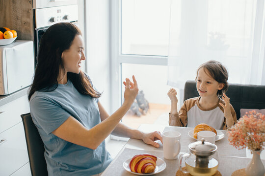 Mother and son communicating in sign language at breakfast table