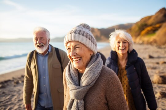 Three happy senior friends are walking on the beach and laughing during a beautiful sunny day
